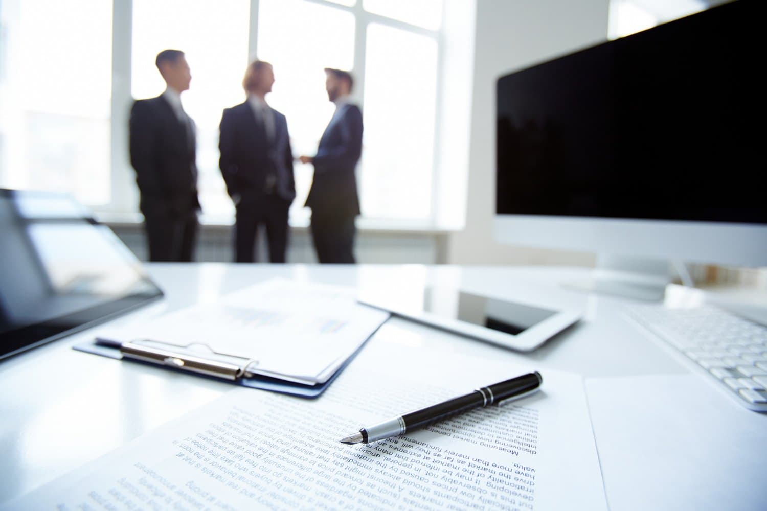 Colleagues in conversation beside a desk with documents and a pen